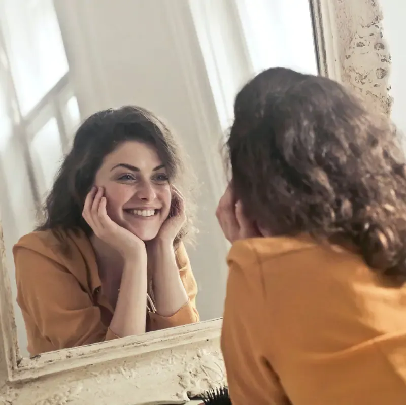 mujer sonriente frente a un espejo