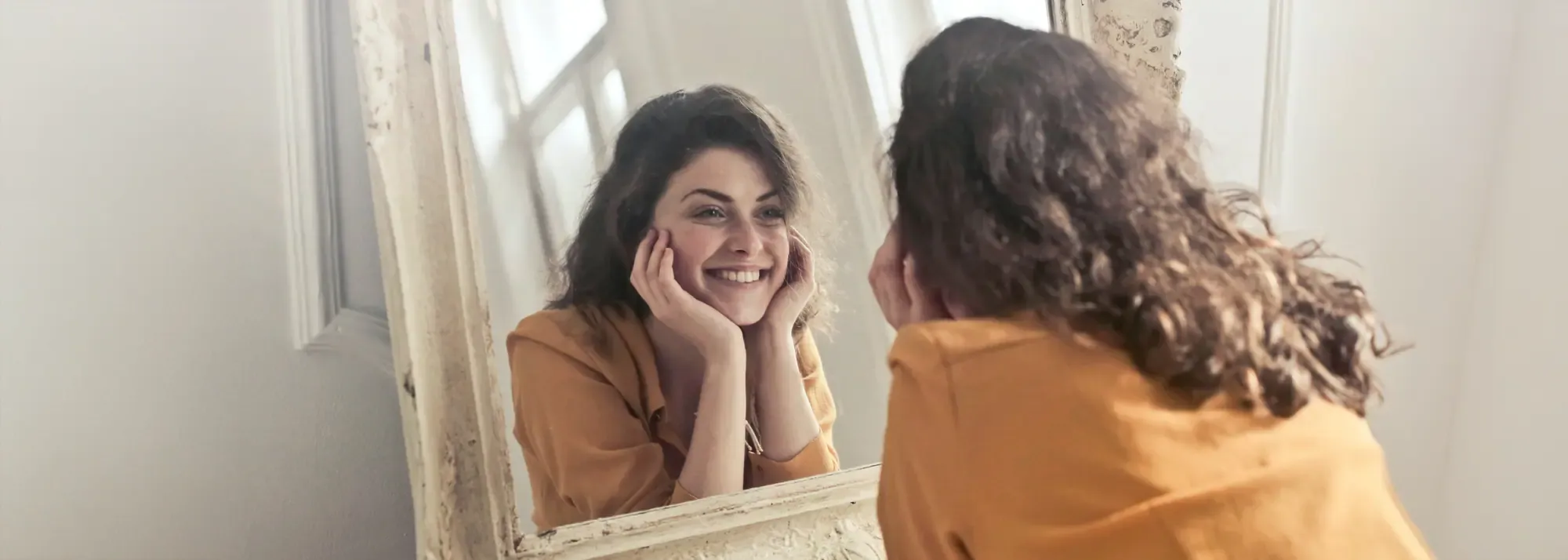 mujer sonriente frente a un espejo